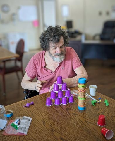 A resident preparing to knock down a mini solo cup tower with a tiny rubber chicken