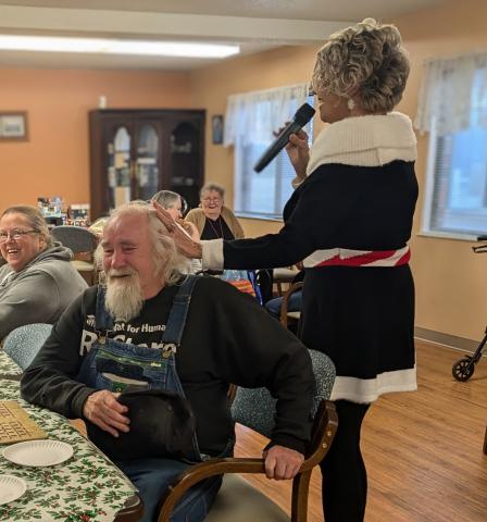 Melissa Tewers sings Santa Baby and teases Bub at Hardin Crest while other residents smile and enjoy the performance.